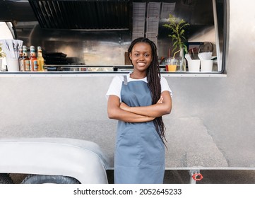 Young female waitress with long braids standing at food truck wearing apron - Powered by Shutterstock