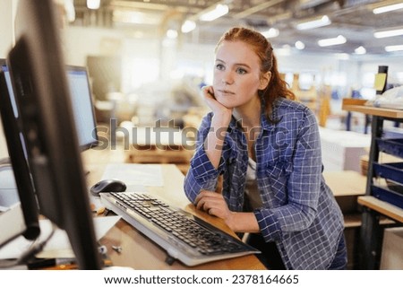 Young female warehouse worker using a computer