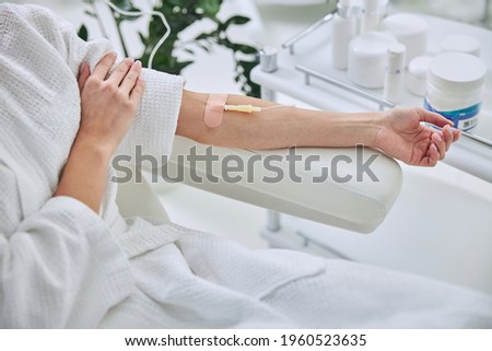 Young female in white bathrobe during medical procedure in beauty clinic