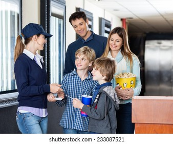 Young Female Worker Checking Tickets Of Family At Cinema