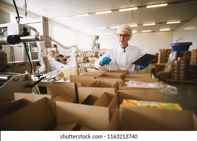 Young Female Worker In Sterile Clothes Is Using Tablet To Check Right Number Of Packages.