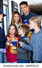 Young Female Worker Taking Movie Tickets From Family At Cinema