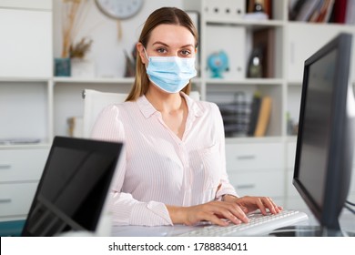 Young Female Worker Wearing Medical Facial Mask Engaged In Business Activities In Office