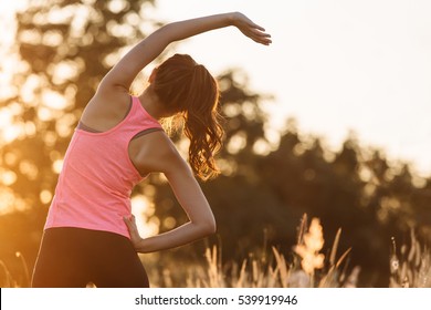 Young female workout before fitness training session at the park. Healthy young woman warming up outdoors. She is stretching her arms and looking away,hi key. - Shutterstock ID 539919946
