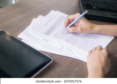 Young female is writing notes and planning her schedule, on wooden desk in modern office. - Shutterstock ID 1074317576