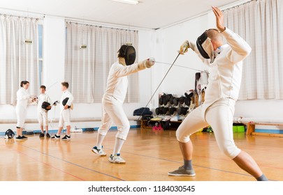 Young fencers looking at fencing duel with foils of two professional athletes in gym
 - Powered by Shutterstock