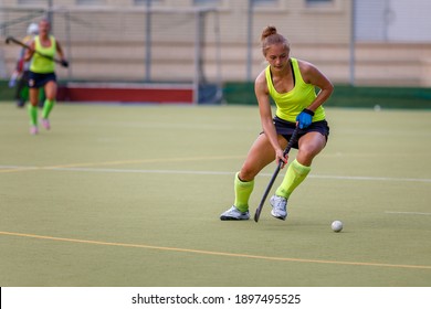 Young Field Hockey Female Player In Attack. Sporty Woman Player Leads The Ball