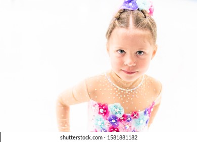 Young Figure Skater In A Pink Dress With Flowers And Rhinestones On The Indoor Ice Arena.