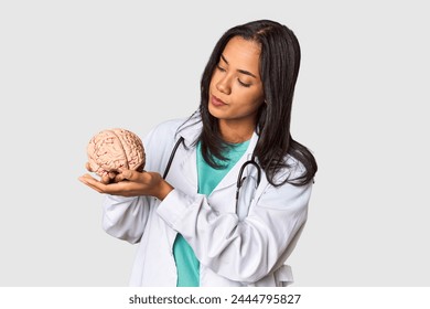 Young Filipina doctor holding a brain model in studio - Powered by Shutterstock