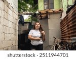 A young Filipina woman walking around an alley in a slum area, stroking her hair while looking pensively around her surroundings.