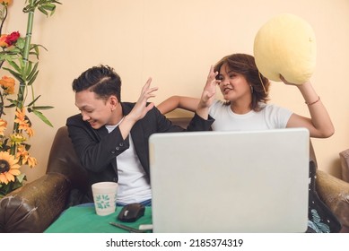 A Young Filipino Couple Play Fighting. Pounding Her Boyfriend Playfully With A Stuffed Toy.