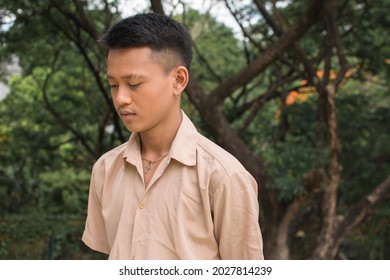 A young Filipino man walks at the park, looking down and gloomy after being busted and turned down by the girl of his dreams.