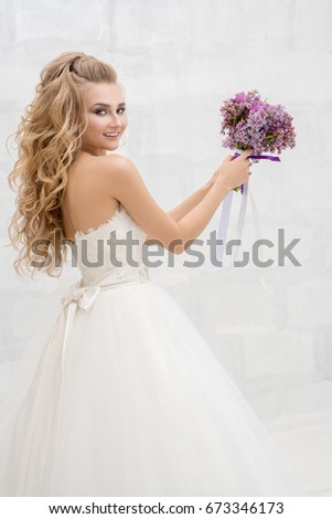 Young fine bride in studio throwing her bouquet
