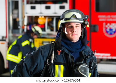 Young Fireman In Uniform Standing In Front Of Firetruck, He Is Ready For Deployment