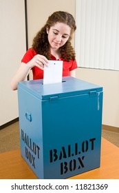 Young First Time Voter Dropping Her Ballot In The Box At The Polling Place.