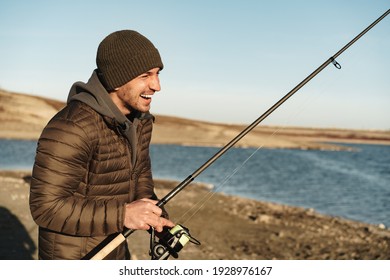 Young Fisherman Standing On The Shore Of Lake With Fishing Rod