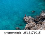 Young fishermen fishing on the rocks from the blue sea in Antalya, Turkiye. 