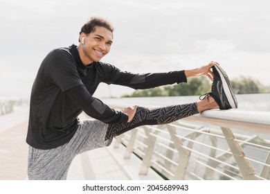 Young fit african male athlete stretching his leg on city urban bridge in fitness outfit. Warming-up activity exercises outdoors. Active lifestyle concept - Powered by Shutterstock