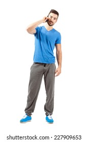 Young Fit Athlete In Sportswear Talking On The Phone Looking At Camera. Full Body Length Portrait Isolated Over White Background.