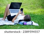 Young fit attractive hipster woman sitting on mat, green lawn in park, working browsing surfing, blogging, eshopping, using pc laptop computer. Wireless 5g internet concept. High quality photo