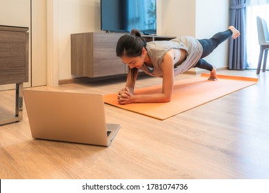 Young Fit Beautiful Asian Woman In Sportswear Workout Exercise (plank) In Living Room On Yoga Mat With Laptop. Workout From Home And Online Training Concept During Covid 19 Pandemic Outbreak