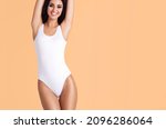 Young, fit and beautiful brunette woman in white swimsuit posing in studio. Concept of fitness, dieting and skin care.