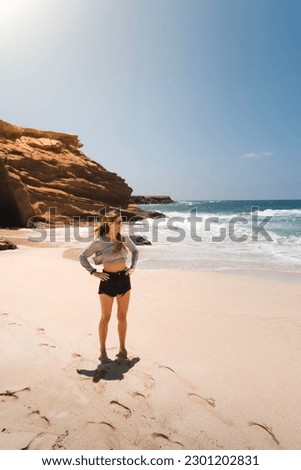 Young fit Caucasian woman looking at the sea at Playa de los Ojos, on the Canary Island of Fuerteventura during her summer vacation.