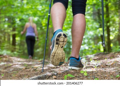 Young fit couple hiking in nature. Adventure, sport and exercise. Detail of male step, legs and nordic walking poles in green woods. - Powered by Shutterstock