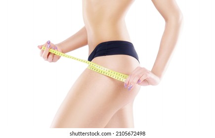 Young and fit female body close-up. Waist of beautiful and slender woman with measuring tape isolated on white. Sport, fitness, diet and healthy eating concepts.