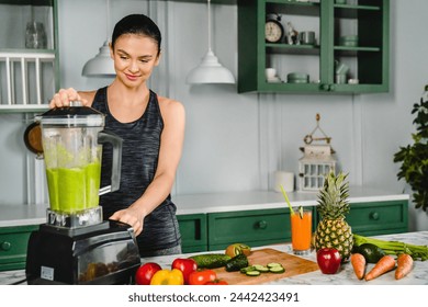 Young fit girl making organic vegan smoothie using blender in the kitchen. Healthy eating habits, dieting and body shape meal. Dietary fresh detox cocktail, super food - Powered by Shutterstock