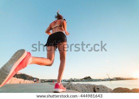 Young fit girl is running alone at beautiful sunset near the sea. Summer sport, freedom concept and healthy lifestyle.