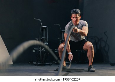 Young Fit Handsome Muscular Man In Activewear Working Out Heavy Battle Rope At The Gym. Motivation Concentration Endurance Exercise.