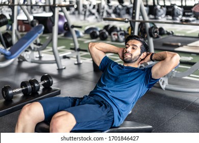 Young fit handsome smiling Caucasian man exercising by doing a sit-up on bench in gym or fitness club. Male athlete has good body shape with six pack. Sport recreation and fitness for health concept. - Powered by Shutterstock