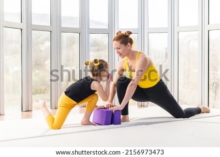 Young fit mother being playful with her daughter before yoga practice