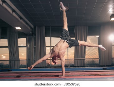 Young Fit Muscular Athletic Adult Man, Young Man One Hand Cartwheel. Large Hall.