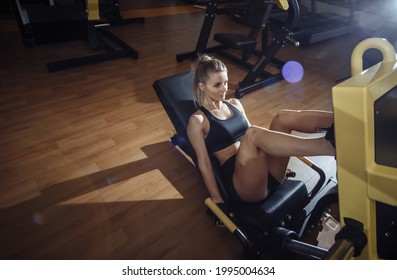 Young Fit Sport Woman Trains Leg Muscles In Exercise Machine In Gym