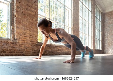 Young Fit Sporty Active Woman Wear Sportswear Standing In Plank Pose Doing Yoga Fitness Training Workout Stretching Core Push Up Pushup Exercise On Wooden Floor In Modern Sunny Gym Space Indoors.