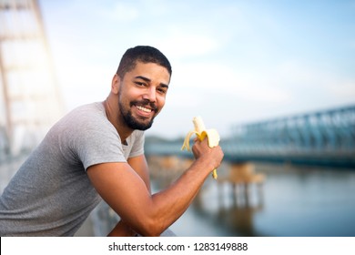 Young Fit Sporty Person Eating Banana And Smiling. Active Lifestyle And Healthy Eating.