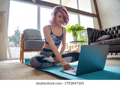 Young Fit Sporty Teen Hipster Girl Pink Hair Wears Sportswear Searching Online Fitness Yoga Class Using Laptop Computer Sitting On Mat At Home. Online Fitness Workout Video Tutorial Virtual Coach.