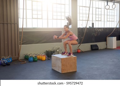 Young fit woman doing box jumps in industrial gym, good form posture technique