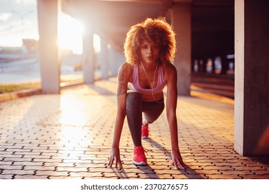 Young fit woman doing a crouch start before running under a bridge in the city - Powered by Shutterstock