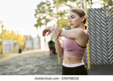 Young fit woman doing hand stretching on the sports ground. Healthy lifestyle.