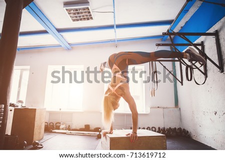 young fit woman doing a handstand exercise at a cross fit gym.