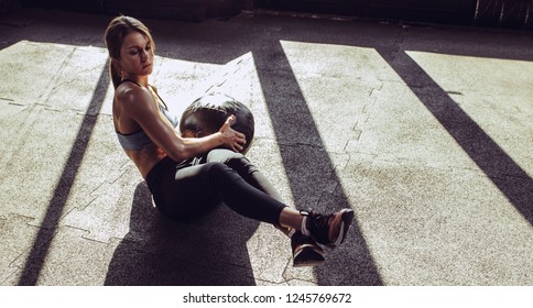 Young fit woman exercising with heavy ball at gym - Powered by Shutterstock