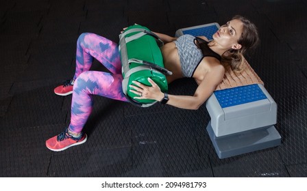Young fit woman is exercising with a sandbag in the gym. Glute bridge