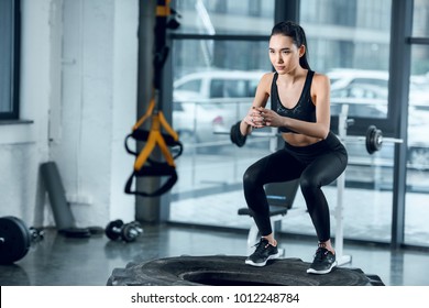young fit woman jumping on workout wheel at gym - Shutterstock ID 1012248784