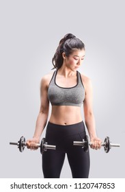 Young Fit Woman Lifting Dumbell On Gray Background