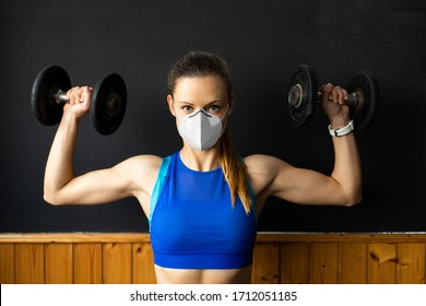 Young Fit Woman With N96 Face Mask  Doing Shoulder Press Exersice At The Gym With Dumbbells. Fitness Strength Workout Under Coronavirus Health Crisis.