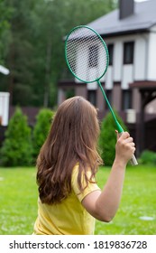 Young Fit Woman Playing Badminton Outdoors. Badminton Player Holds Racket In Action. Sport, Youth, Activity, Power, Confidence, Energy, Summer, Game, Hobby, Leisure Concept. Back View