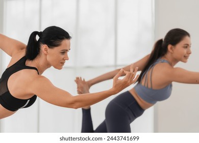 A young fit woman practices yoga by doing asanas in a bright yoga studio. Yoga practitioner with students in yoga class. - Powered by Shutterstock